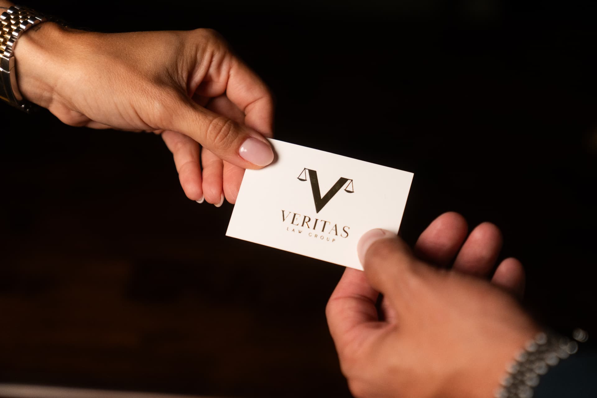 A Veritas Law Group business card being handed to a client